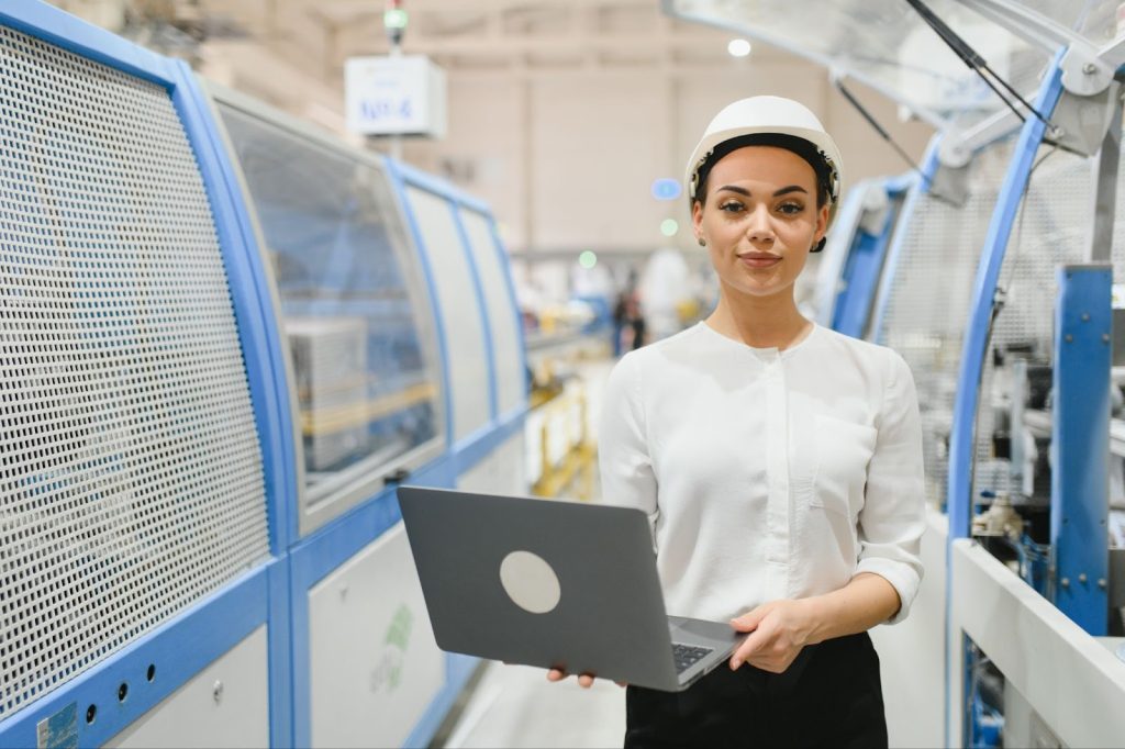Female factory worker walking down the smart factory with a laptop