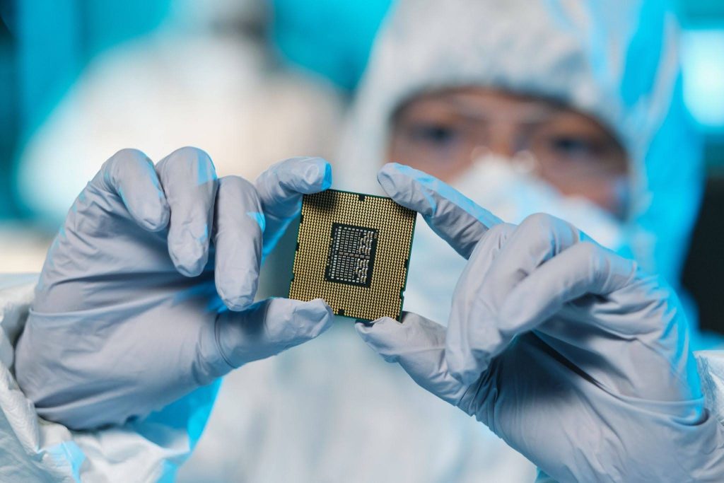 worker examining semiconductor chip in cleanroom